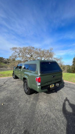2022 Toyota Tacoma TRD Off Road 4WD in green with camper shell on a scenic view