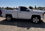 2014 Chevrolet Silverado 1500 LT 4WD in white with chrome wheels parked on gravel, showcasing its sleek design.