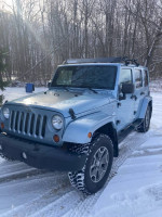 2012 Jeep Wrangler Unlimited Rubicon in blue, parked on snowy ground, showcasing its rugged design.