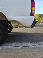Side view of a 2002 Chevrolet Silverado showing minor damage and wear, highlighting its work truck history.
