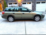 2006 Subaru Forester 2.5 X AWD wagon parked in front of a stone garage, showcasing its clean exterior.