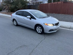 2014 Honda Civic 4-door sedan in silver color parked on the street, showcasing its reliable design and great fuel efficiency.