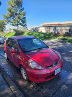 2007 Honda Fit in red color parked on the street, showcasing its compact design and manual transmission features.