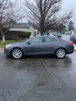 2014 Chevrolet Malibu LTZ FWD parked on a wet street, showcasing its sleek design and good condition.