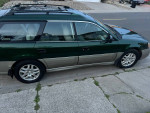 2002 Subaru Outback Legacy in green color, parked on a driveway, showcasing its low mileage and clean exterior.