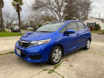 2018 Honda Fit in blue with 98,000 miles parked on a driveway in front of a house.