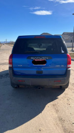 Rear view of a blue 2004 Saturn VUE sport utility vehicle parked on a dirt road.
