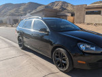 2013 Volkswagen Jetta TDI black sportwagen parked near mountains, showcasing its sleek design and OEM blacked out wheels.