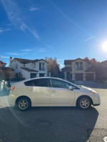 Side view of a white 2011 Toyota Prius Hybrid parked on a residential street, showcasing its sleek design.