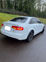 2013 Audi A4 2.0T Premium FWD parked on a wet road, featuring sleek design and modern LED taillights.