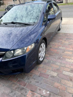 2009 Honda Civic LX in blue, parked on a brick sidewalk, with clean exterior and modern design.
