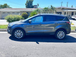Side view of a well-maintained 2018 Ford Escape Titanium in gray, parked in a residential area.