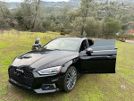 Black 2018 Audi A5 Prestige quattro AWD parked on grassy area, showcasing its design and open doors.