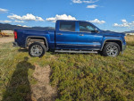 2014 GMC Sierra 1500 SLT 4WD in cobalt blue, side view showcasing its crew cab and 20-inch wheels.