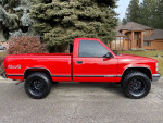1997 GMC Sierra 1500 SL 4WD in red, showing side view with new black wheels and tires, parked outdoors
