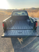 View of the bed of a 1999 GMC Sonoma SLS Sport 4WD truck with clear sky and landscape background.