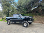 2006 Chevrolet Silverado 1500 with 4x4, 8" lift and new mud terrain tires parked on a country road