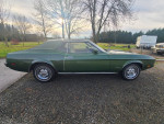 Side view of a 1973 Ford Mustang Grande, green color, showing its original condition and vintage design.