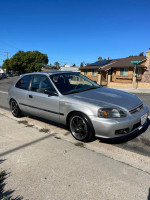 2000 Honda Civic hatchback in silver, parked on the street with a clear blue sky, showcasing its sporty design
